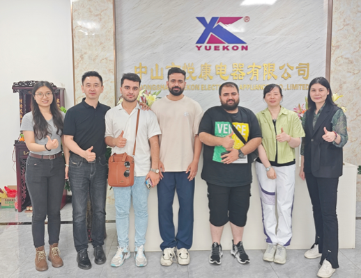 Les employés de Zhongshan Yuekon Electrical Appliances Co., Limited et les clients internationaux posant ensemble, symbolisant une relation commerciale fructueuse et collaborative.